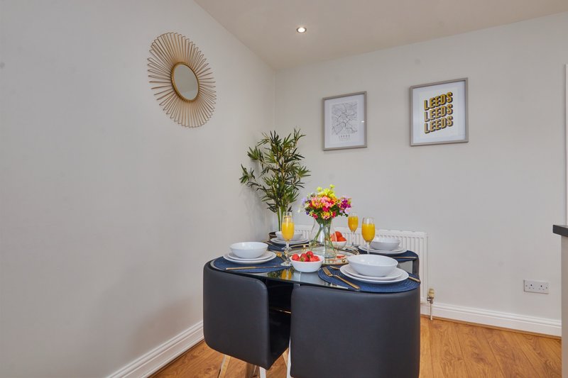 Dining area with round black table, place settings, flowers, and wall decor