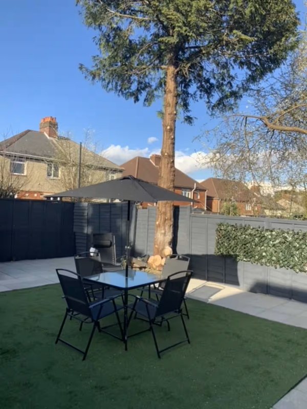 Garden patio area with table, chairs, umbrella and artificial grass surrounded by fencing