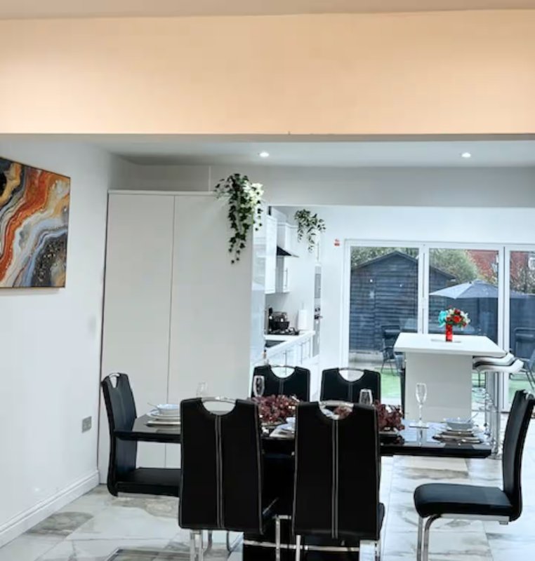 Modern dining area with black table, chairs, and garden view through glass doors