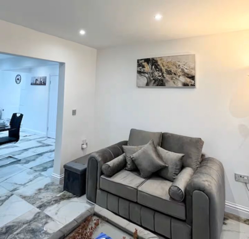 Modern living room with gray upholstered sofa, decorative cushions, and landscape artwork on wall