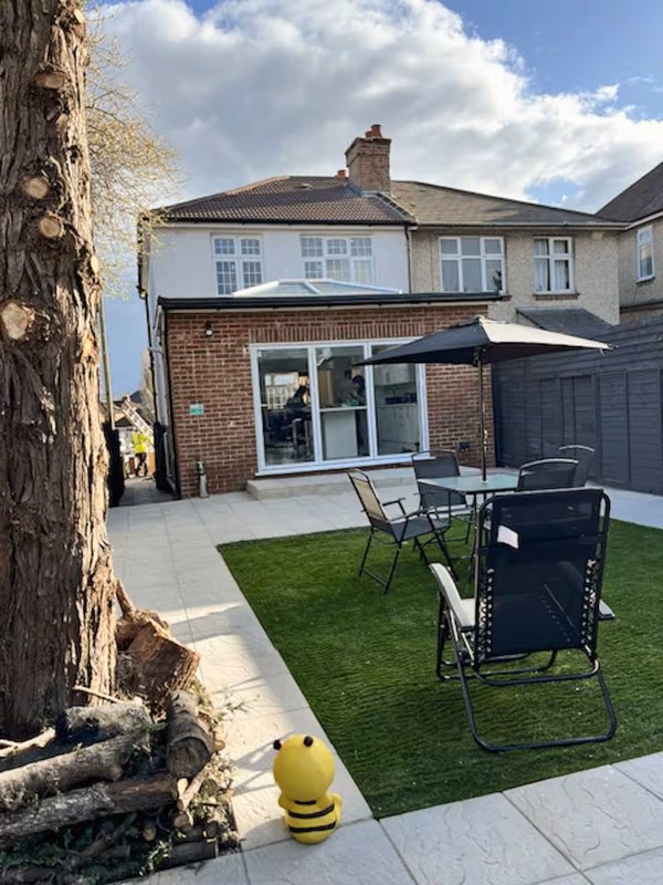 Suburban garden with patio, garden chairs, artificial grass and brick extension