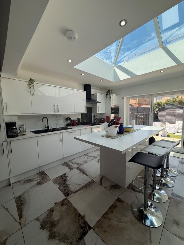 Modern kitchen with white cabinets, island seating, skylight, and garden view