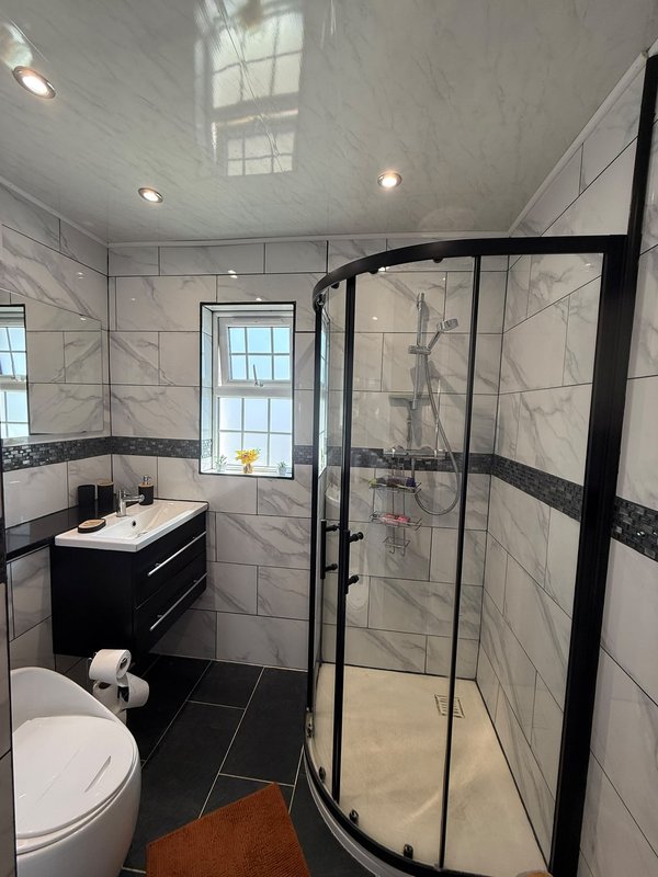 Modern bathroom with black and white tile, shower enclosure, vanity sink and window