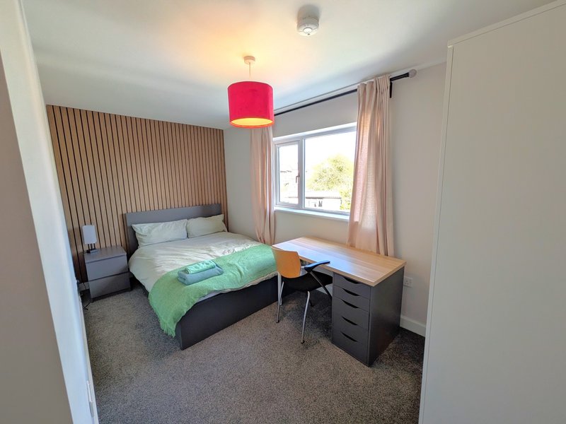 Bedroom with double bed, desk, chair, red pendant light and window