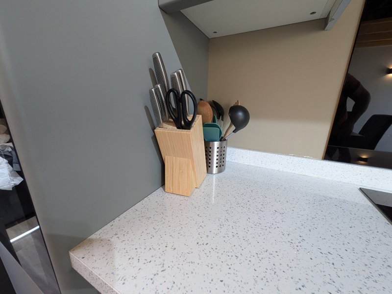Kitchen counter with speckled white surface, knife block, and cooking utensils
