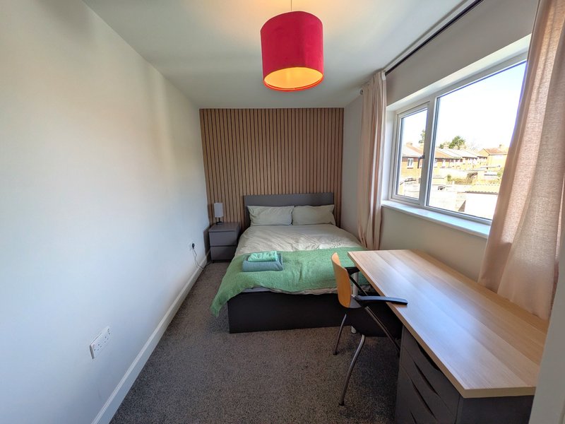 Modern bedroom with single bed, red ceiling lamp, desk, and large window with countryside view