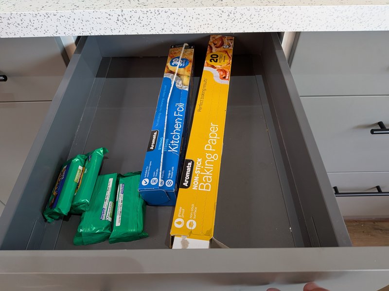 Kitchen drawer with storage boxes, green containers, and packaged household items