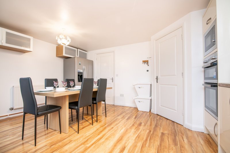 Modern kitchen-diner with wooden table, black chairs, built-in appliances and light wood flooring