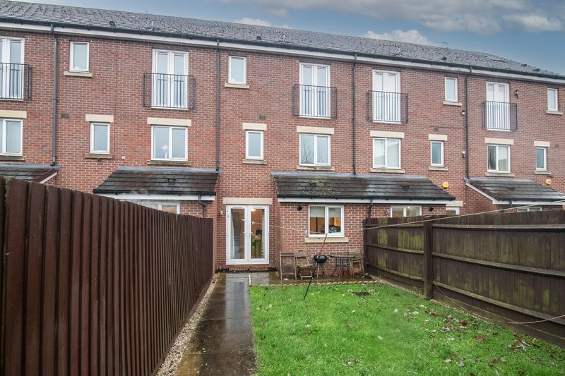 Brick terraced house with patio area, garden fence and green lawn