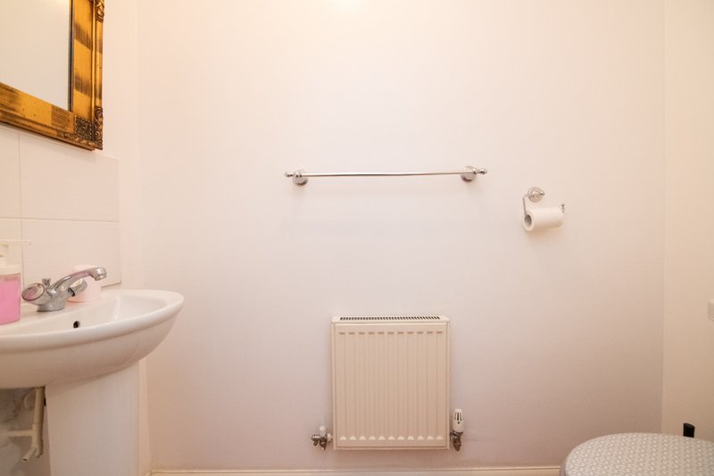 Small bathroom with pedestal sink, radiator, towel rail and toilet