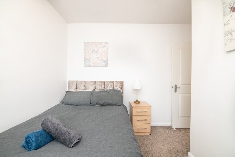 Bedroom with double bed, grey bedding, wooden nightstand and wall art
