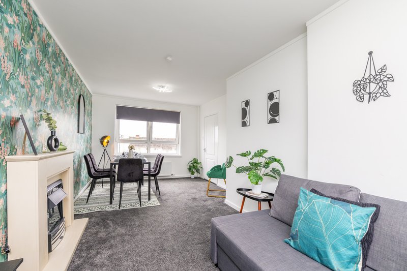 Open-plan living area with sofa, dining table, fireplace and patterned wallpaper