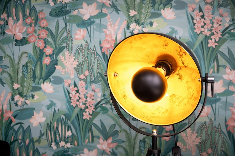 Yellow desk lamp with floral wallpaper featuring pink flowers and green foliage