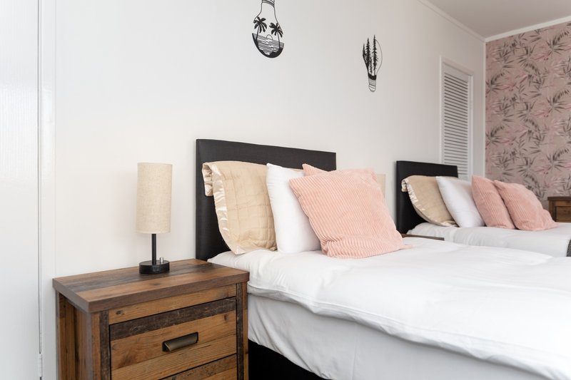 Modern bedroom with black bed frame, decorative pillows, wooden nightstand and bedside lamp