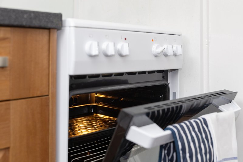 Kitchen oven with open door and striped towel hanging on handle