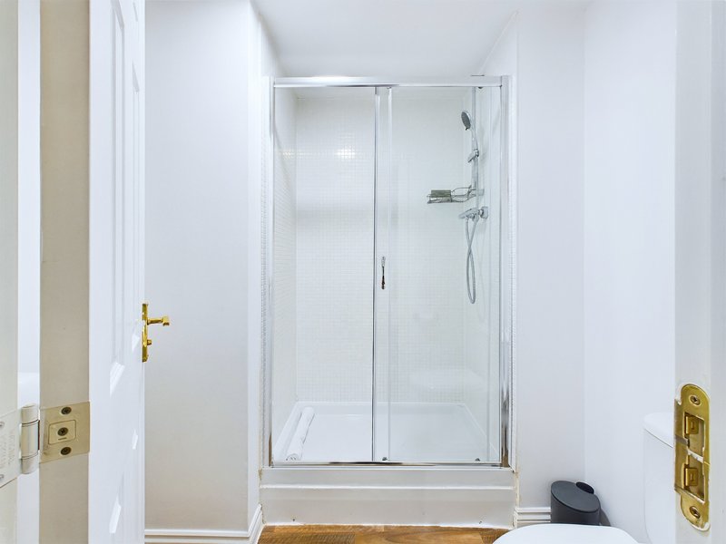 Modern bathroom with walk-in shower, white tiles, gold fixtures and door handle