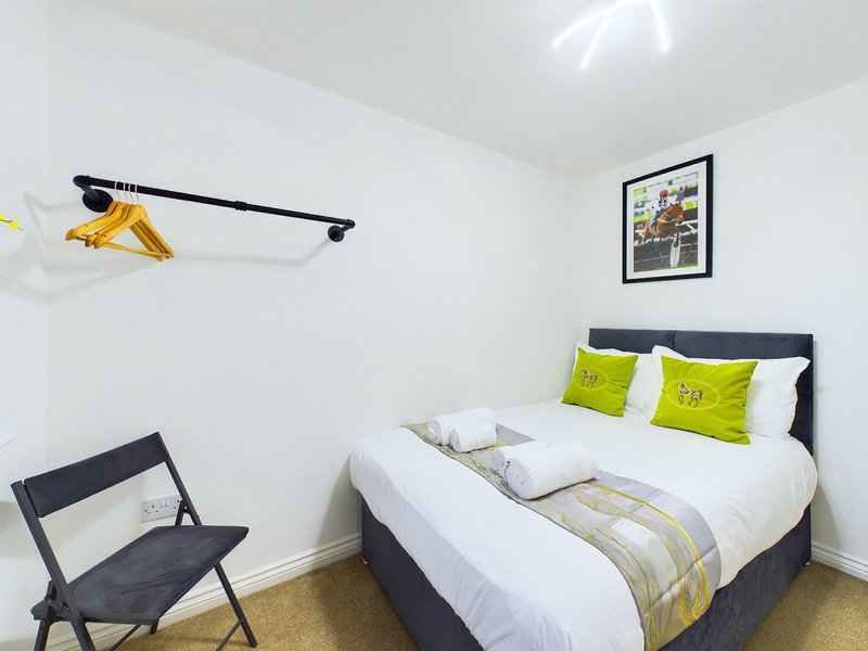 Modern bedroom with double bed, lime green pillows, black chair, and framed wall art