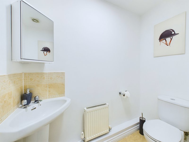 Clean bathroom with sink, mirror cabinet, toilet, radiator and framed artwork
