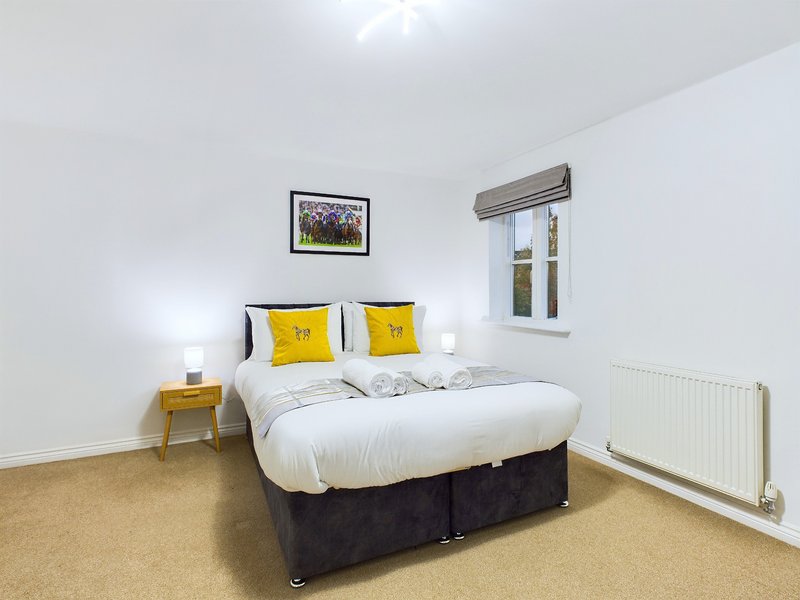 Bright modern bedroom with double bed, yellow cushions, wooden nightstand and window