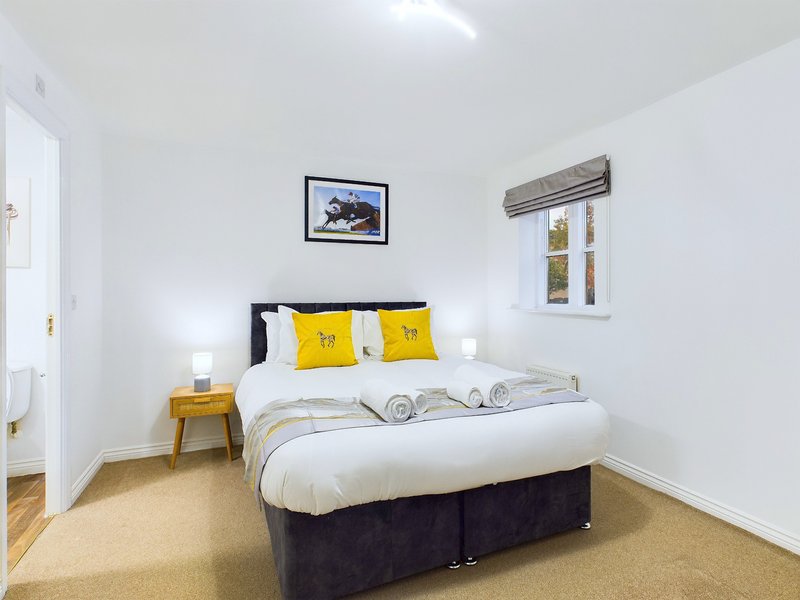 Bright bedroom with double bed, yellow pillows, wooden nightstand and framed wall art