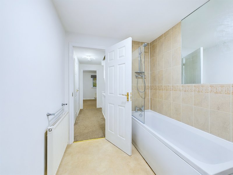 Modern bathroom with white bath, tiled shower enclosure, beige tiles and white door