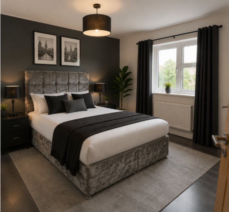 Modern bedroom with grey upholstered bed, black bedding, pendant light and framed wall art
