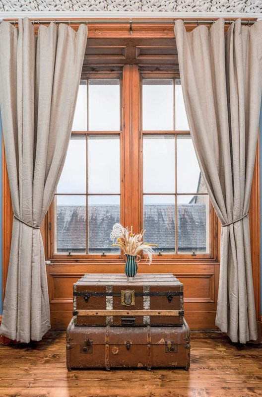 Wooden window with cream curtains, vintage suitcases, and mountain view