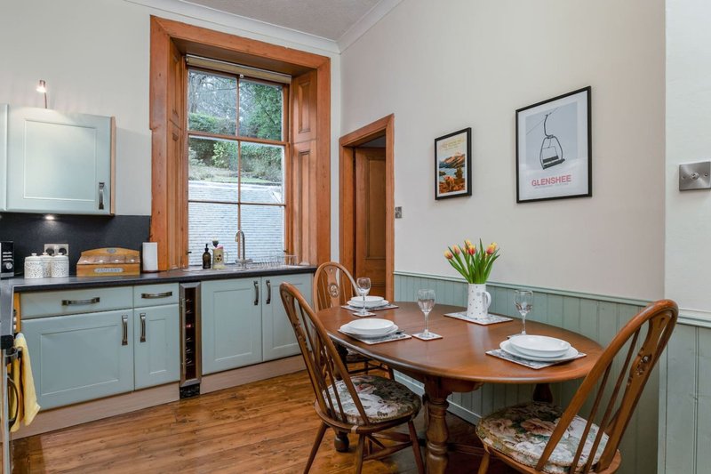 Kitchen-diner with blue cabinetry, wooden table, chairs, and framed wall art