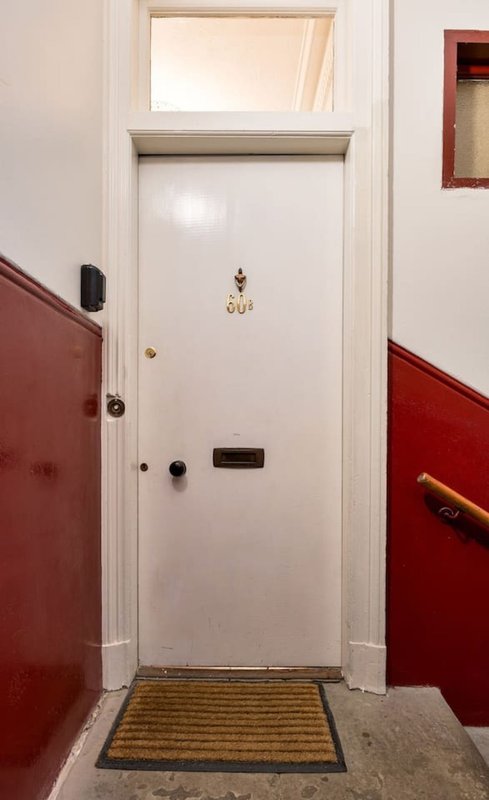 Entryway with white door, red walls, doormat and wall-mounted fixtures