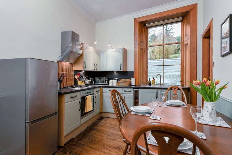 Modern kitchen and dining area with stainless steel appliances, wooden table, chairs and large window