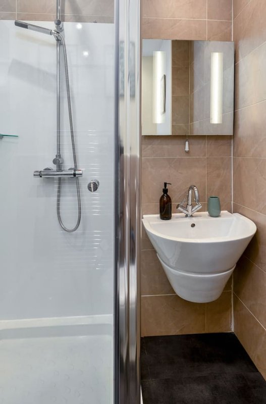 Modern bathroom with walk-in shower, wall-mounted sink, mirror cabinet and brown tile walls