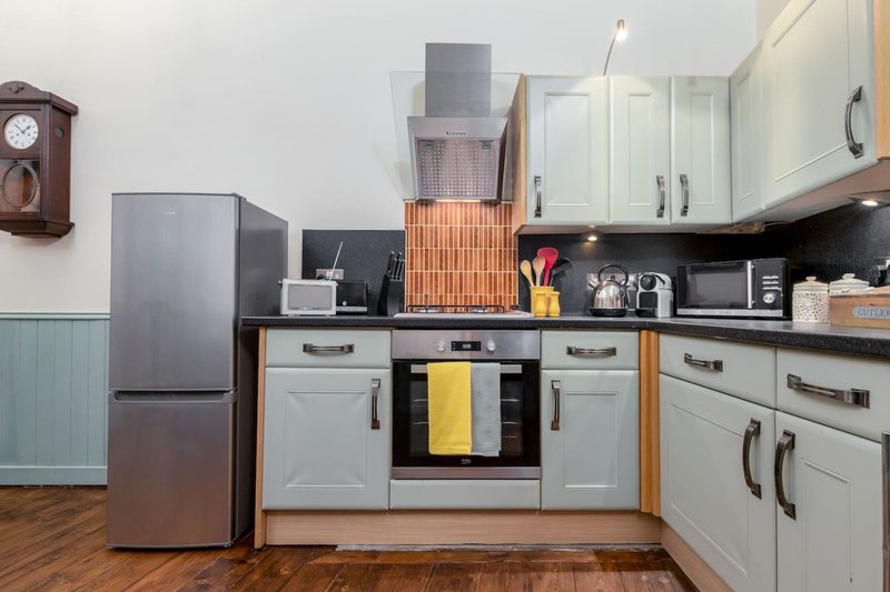 Modern kitchen with white cabinetry, stainless steel appliances, and wooden flooring