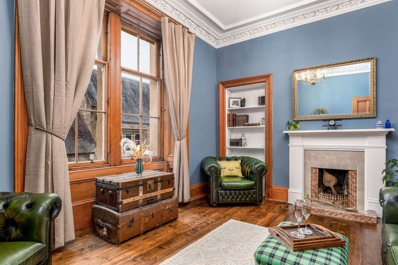 Traditional living room with fireplace, green leather armchair, wooden window frame and hardwood flooring
