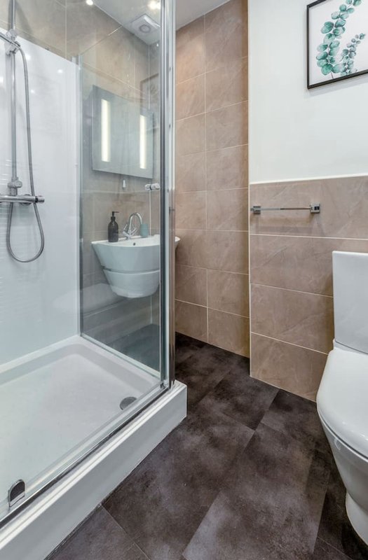 Modern bathroom with walk-in shower, toilet, sink and dark tile flooring