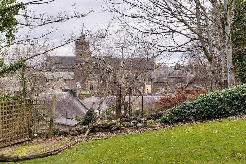 Garden view overlooking town with church spire, bare trees and green lawn