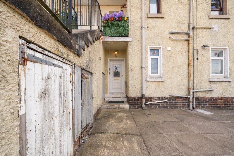 Stone terraced house exterior with white garage door, entrance, and driveway