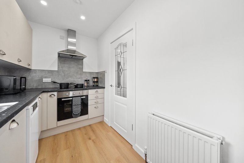 Modern kitchen with cream cabinets, dark worktops, built-in oven and wooden flooring