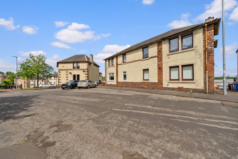 Exterior view of stone and brick residential building with parking area and street frontage