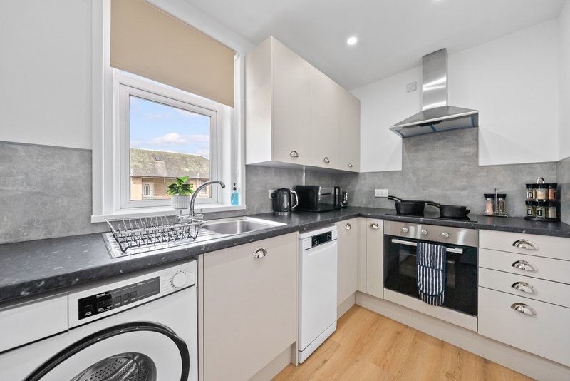 Modern kitchen with white cabinets, black countertops, integrated appliances and window
