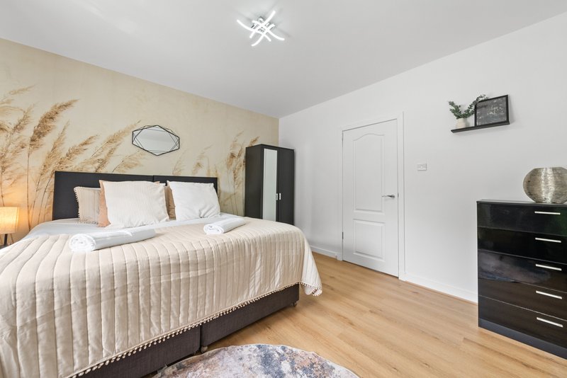 Modern bedroom with queen bed, wooden flooring, black furniture and neutral decor