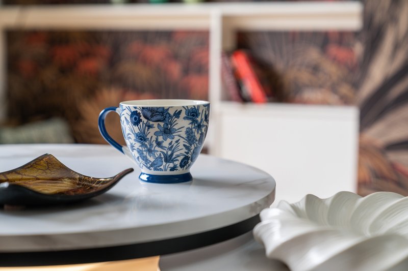 Decorative table with blue patterned cup, ceramic dish, and white napkin indoors