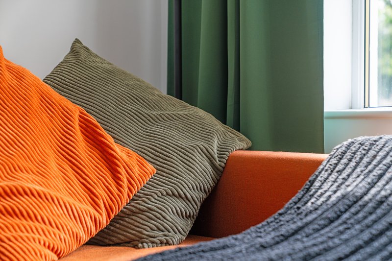 Bedroom detail with colorful decorative pillows and textured bedding near window