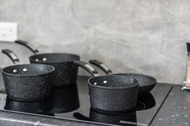 Three black speckled cooking pans on electric stovetop in modern kitchen