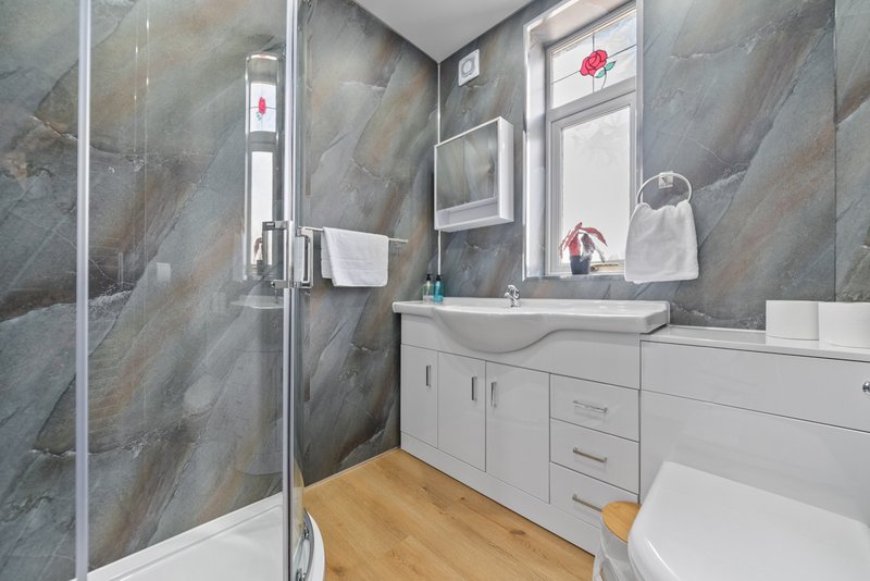Modern bathroom with grey marble tiles, white vanity, mirror and wooden flooring
