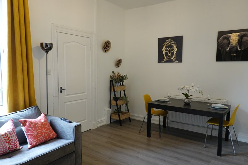 Modern living room with sofa, dining table, chairs, artwork and yellow curtains