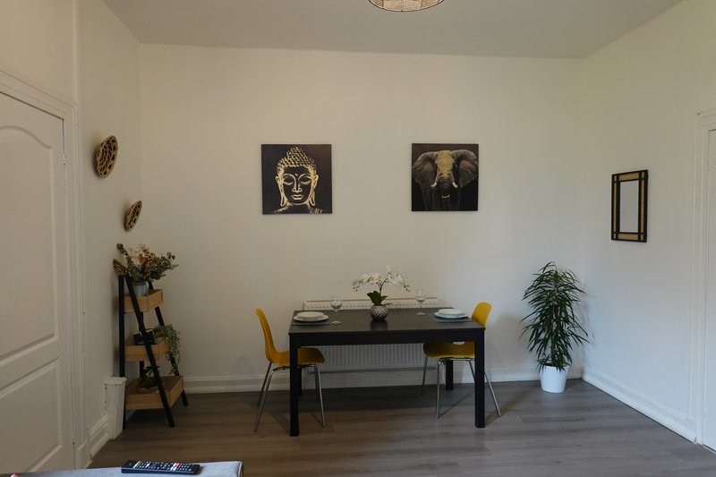 Dining room with black table, yellow chairs, wall art and potted plant