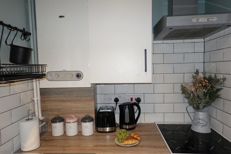 Modern kitchen with white subway tiles, wooden worktop, appliances and coffee maker