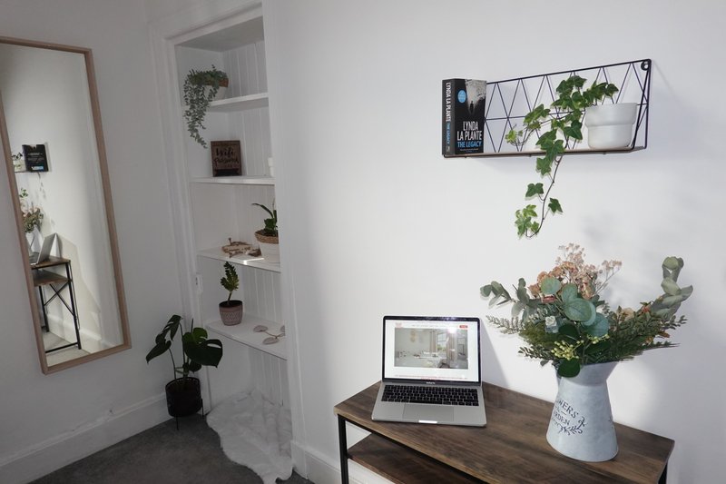 Bright modern bedroom with desk, laptop, potted plants, wall shelves and full-length mirror