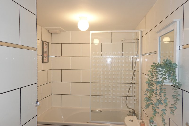 Modern bathroom with walk-in shower, cream subway tiles, glass enclosure and potted plant