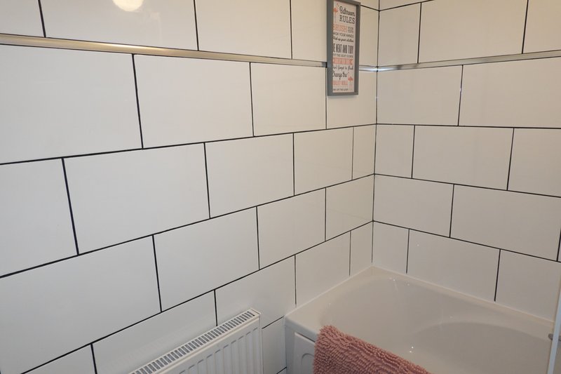 Bathroom with white subway tile walls, bathtub, and folded towel